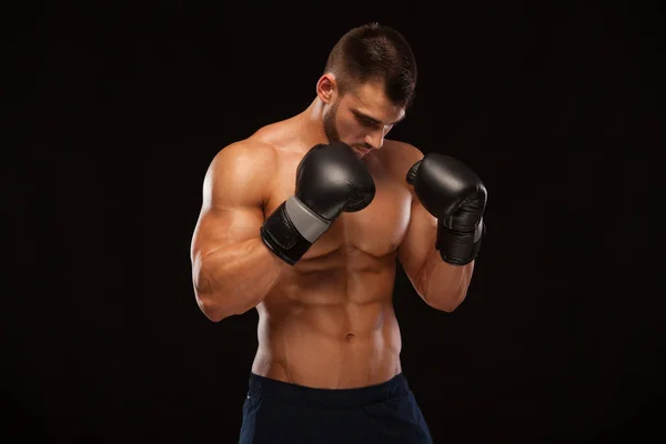 Muskulös ung man med perfekt Torso med sex pack abs, i boxning handskar visar olika rörelser och slår isolerade på svart bakgrund med copyspace — Stockfoto