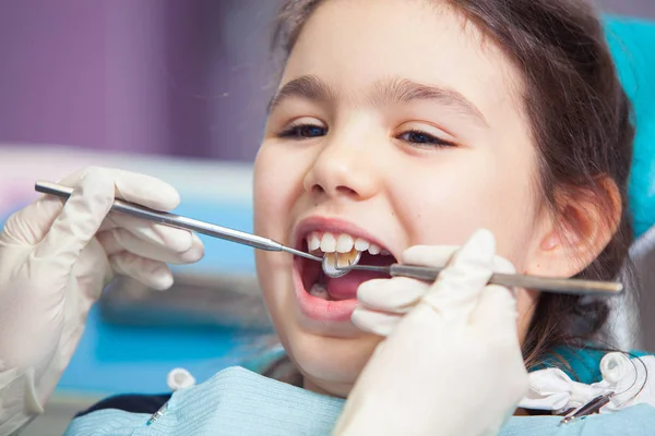 Close-up de menina bonita abrindo a boca durante o tratamento de seus dentes pelo dentista — Fotografia de Stock