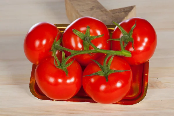 Five fresh red tomatoes with green stem in the tray , isolated on the background — Stock Photo, Image