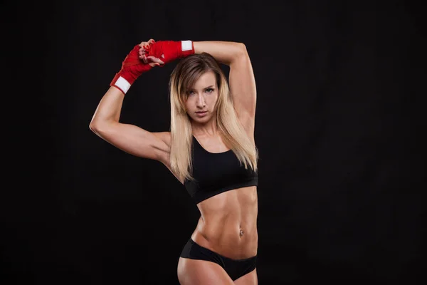 Атлетичная девушка, позирующая в красных бинтах, изолированная на темном фоне боксерского боксерского боксерского кикбокса — стоковое фото