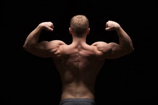Pokazano fitness model lekkoatletycznego przystojny mężczyzna, jego mięśni pleców, na białym tle na czarnym tle z lato — Zdjęcie stockowe