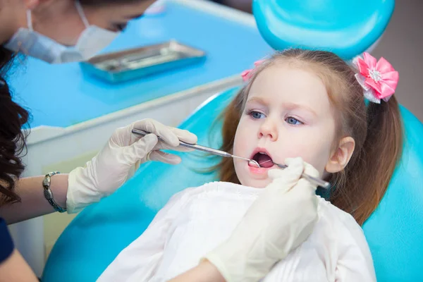 Primer plano de la niña bonita abriendo la boca durante la inspección de la cavidad oral en el dentista — Foto de Stock