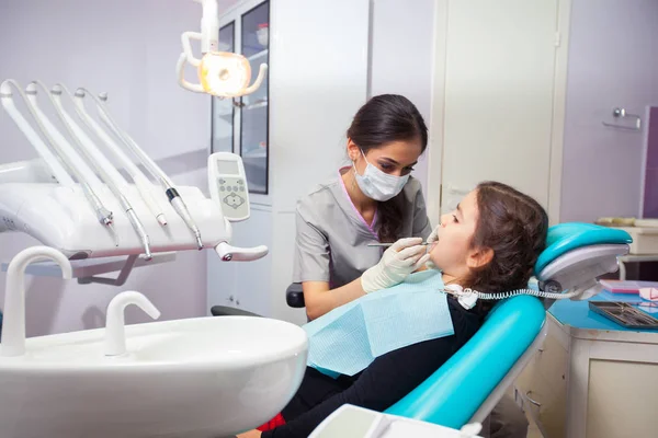 Hübsches kleines Mädchen, das seinen Mund weit öffnet, während der Zahnarzt ihre Zähne behandelt — Stockfoto