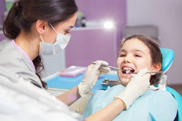 Nahaufnahme eines hübschen kleinen Mädchens, das seinen Mund weit öffnet, während der Zahnarzt ihre Zähne behandelt — Stockfoto
