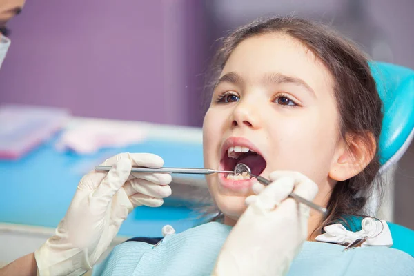 Close-up of pretty little girl opening his mouth wide during treating her teeth by the dentist — Stock Photo, Image