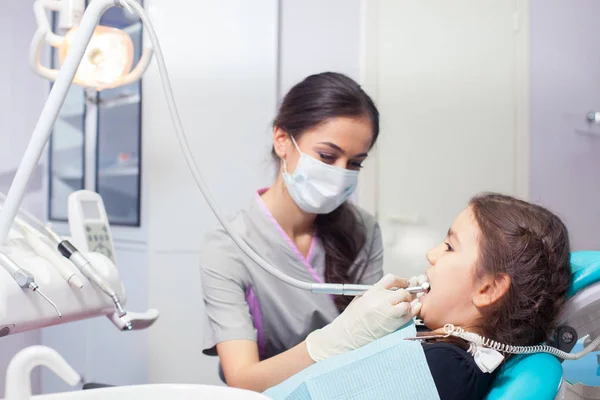 Primer plano de la hermosa niña abriendo la boca durante el tratamiento de sus dientes por el dentista —  Fotos de Stock