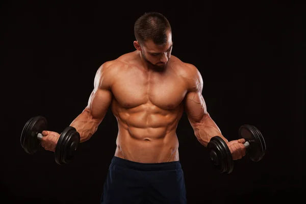 筋肉のハンサムな男は、ジムでダンベル トレーニングです。copyspace と黒の背景に分離 — ストック写真