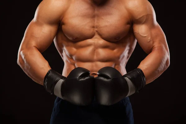 Muscolare giovane uomo con perfetto busto con sei pack abs, in guantoni da boxe sta mostrando i diversi movimenti e colpi isolati su sfondo nero con copyspace — Foto Stock