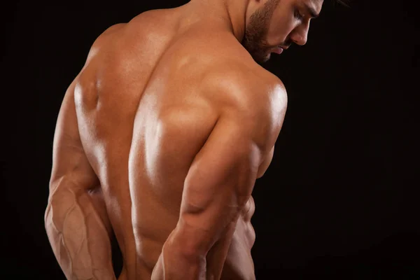 Homem Atlético Forte Modelo Fitness mostrando suas costas perfeitas isoladas em fundo preto com copyspace — Fotografia de Stock