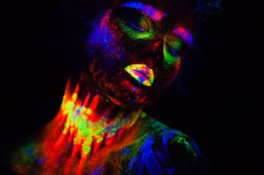 Beautiful extraterrestrial model woman in neon light. It is portrait of beautiful model with fluorescent make-up, Art design of female posing in UV with colorful make up. Isolated on black background clipart
