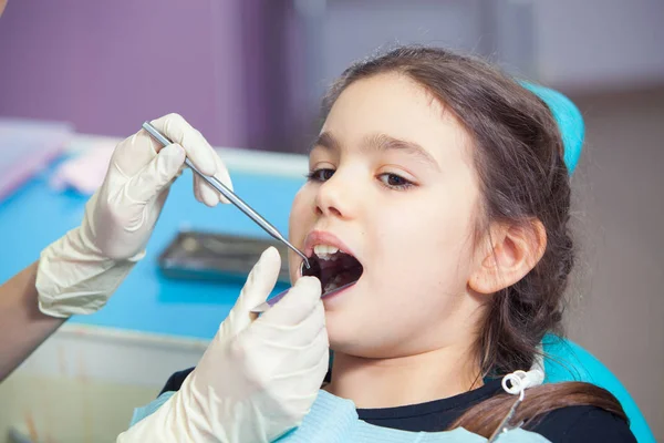 Close-up de menina bonita abrindo a boca durante o tratamento de seus dentes pelo dentista — Fotografia de Stock