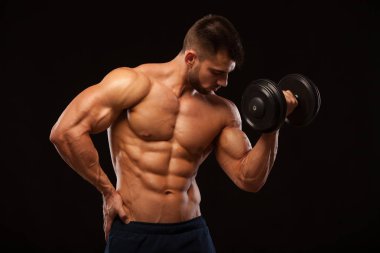 Yakışıklı güç güvenle ileriye dumbbell atletik adamla. Altı paket, mükemmel abs, omuzlar, pazı, triceps ve siyah arka plan ile boşaltmak izole göğüs ile güçlü vücut geliştirmeci