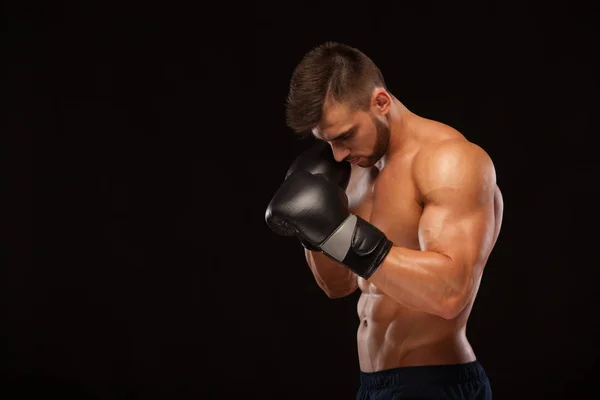 Muscular young man with perfect Torso with six pack abs, in boxing gloves is showing the different movements and strikes isolated on black background with copyspace — Stock Photo, Image