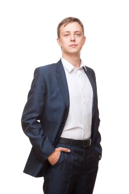 Siyah elbiseli genç yakışıklı işadamı düz duruyor ve ellerini ceplerine koyarak, portre beyaz arka plan üzerinde izole