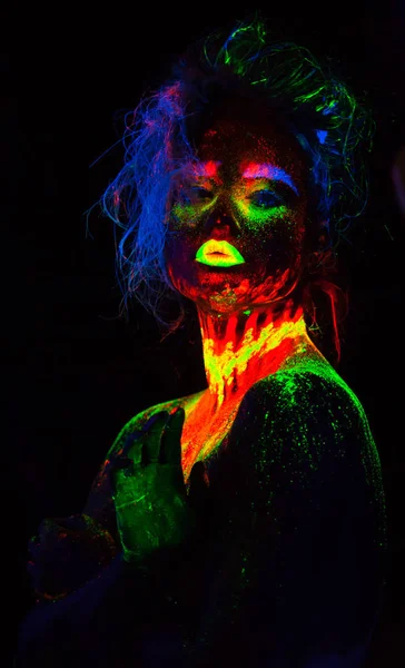 Belle femme modèle extraterrestre avec coiffure bleue et lèvres vertes dans la lumière au néon. C'est portrait de beau modèle avec le maquillage fluorescent, conception d'art de femelle posant dans UV avec le maquillage coloré — Photo
