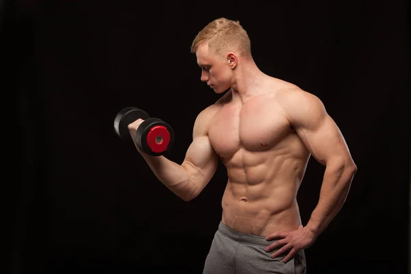 Sportovní krasavec fitness-model je cvičit s činka a ukazuje jeho dokonalé tělo. izolované na černém pozadí s copyspace — Stock fotografie