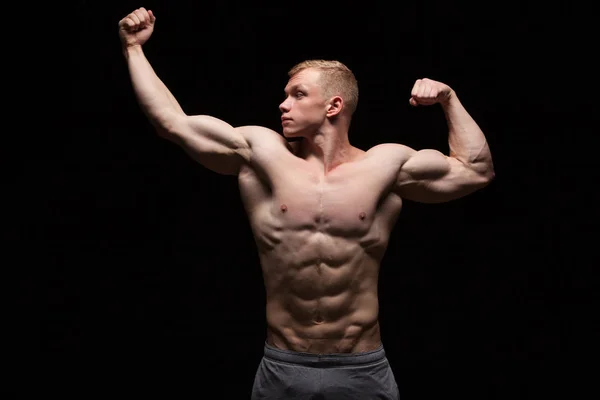 Athletisch gut aussehender Mann Fitness-Model zeigt Sixpack Bauchmuskeln und schaut nach links. isoliert auf schwarzem Hintergrund mit Copyspace — Stockfoto