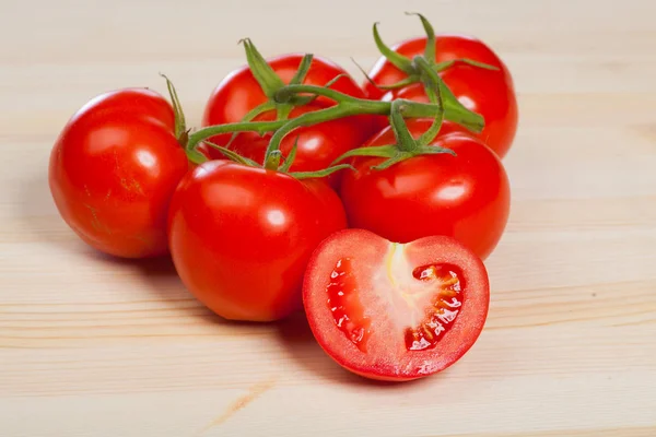 Tomates rojos orgánicos con el tallo en la mesa de madera — Foto de Stock