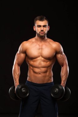 Eğitim salonunda dumbbells ile kas yakışıklı adamdır. siyah arka plan ile boşaltmak izole