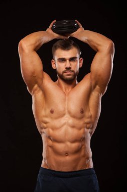Güçlü adam egzersizleri triceps bir dumbbell ile yapmak. Atış eğitim eller yukarı kapatın. Onun gövde altı ile gösterilen fitness modeli bohça abs. boşaltmak siyah zemin üzerine izole