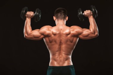 Kaslı erkek model vücut geliştirmeci geri döndü dumbbells ile yapıyor. Siyah arka plan ile boşaltmak izole