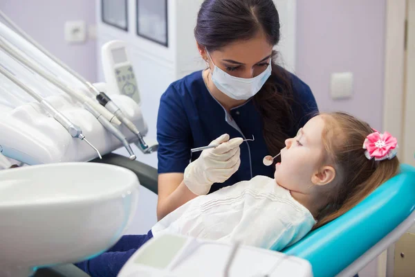 Kobieta dentysty w masce leczy zęby dziewczynka — Zdjęcie stockowe
