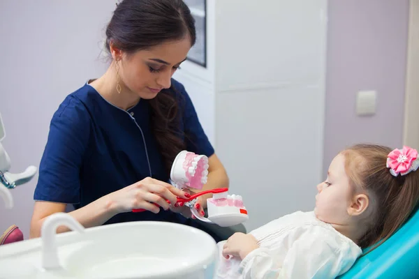 Pediatrické zubař vzdělávání usměvavá holčička o správné zubů, demonstrovat na modelu. Včasné prevence, zvyšování povědomí, ústní hygienu demonstrace koncepce. — Stock fotografie