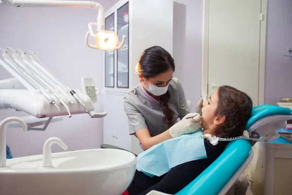 Bonita niña abriendo la boca durante el tratamiento de sus dientes por el dentista — Foto de Stock