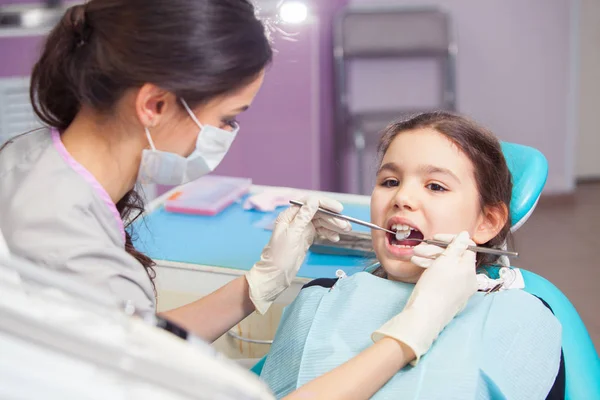 Close-up of pretty little girl opening his mouth wide during treating her teeth by the dentist — Stock Photo, Image