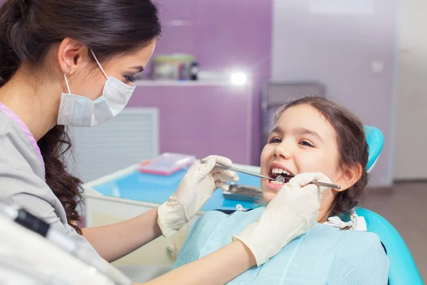 Close-up of pretty little girl opening his mouth wide during treating her teeth by the dentist — Stock Photo, Image