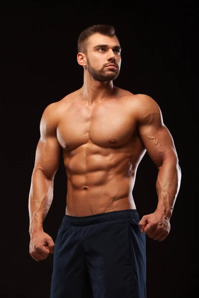 Fitness gespierde man is poseren en tonen zijn torso met zes pack abs. geïsoleerd op zwarte achtergrond met copyspace — Stockfoto