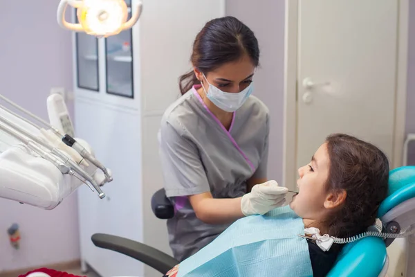 Hübsches kleines Mädchen, das seinen Mund weit öffnet, während der Zahnarzt ihre Zähne behandelt — Stockfoto