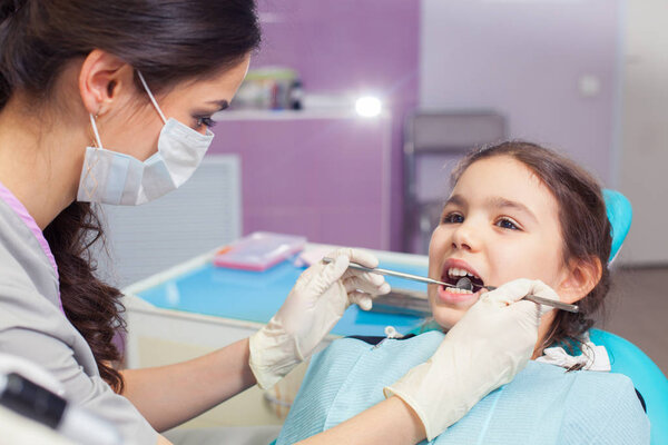 Close-up of pretty little girl opening his mouth wide during treating her teeth by the dentist