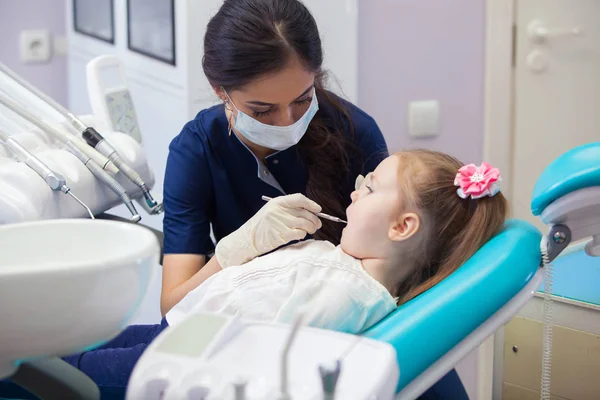 Zubař v masce léčí zuby malou holčičku — Stock fotografie