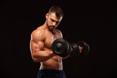 Eğitim salonunda dumbbells ile kas yakışıklı adamdır. siyah arka plan ile boşaltmak izole