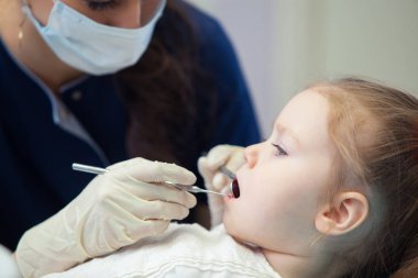 Maskeli kadın diş hekimi diş davranır küçük kız