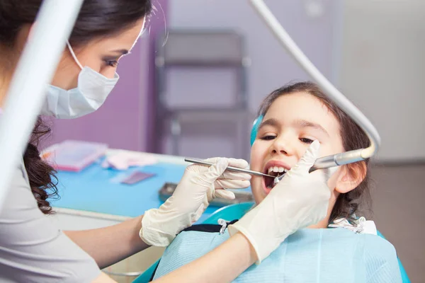 Primer plano de la hermosa niña abriendo la boca durante el tratamiento de sus dientes por el dentista — Foto de Stock