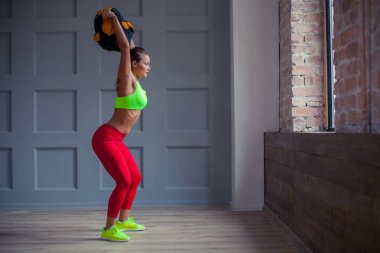 güzel genç kadın spor salonunda bir kum torbası ile eğitiyor.