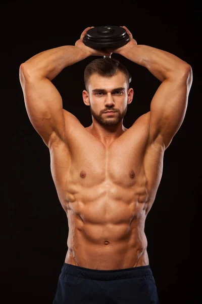 Sterke man maken van oefeningen op triceps met een halter. Close-up shot opleiding handen. Fitness Model toont zijn Torso met zes pack abs. geïsoleerd op zwarte achtergrond met copyspace — Stockfoto