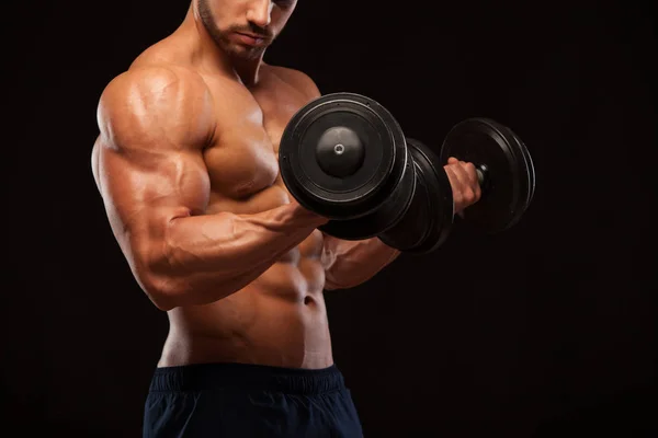 Muscular handsome man is training with dumbbells in gym. isolated on black background with copyspace — Stock Photo, Image