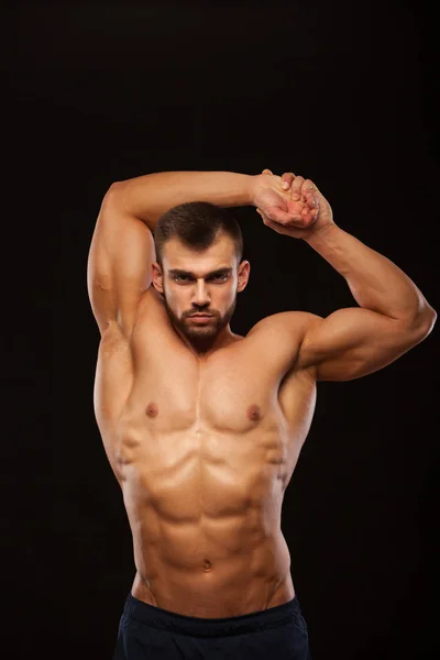 Сильна людина спортивний - фітнес-модель показує його тулуба з шести абс пакет і проведення його руки. ізольовані на чорному фоні з copyspace — стокове фото
