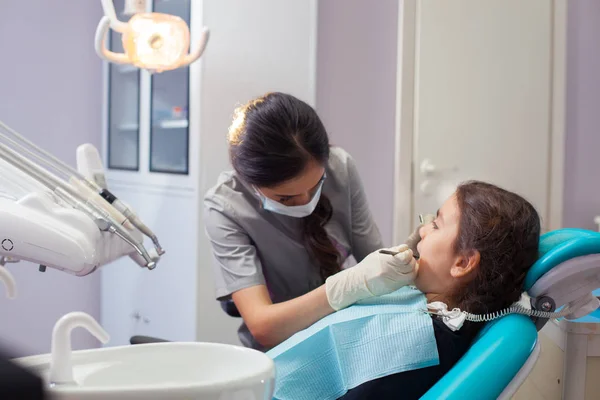 Całkiem mała dziewczynka otwierał usta szeroki podczas leczenia zębów przez dentystę — Zdjęcie stockowe