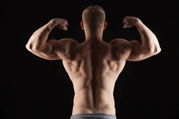 Sportovní krasavec fitness-model obrátil zpět ukazuje své dokonalé tělo. izolované na černém pozadí s copyspace — Stock fotografie