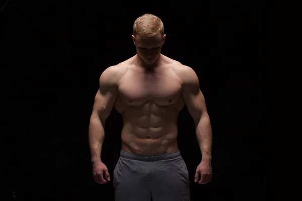 Knappe man van de atletische fitness-model vertoont zes pack abs. geïsoleerd op zwarte achtergrond met copyspace — Stockfoto