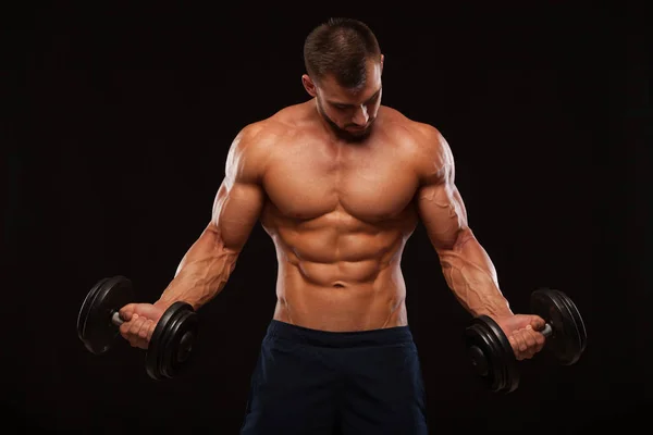Muscular handsome man is training with dumbbells in gym. isolated on black background with copyspace Stock Image