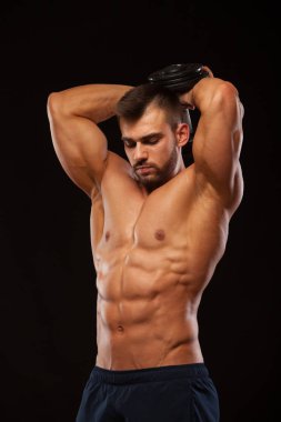 Güçlü adam egzersizleri triceps bir dumbbell ile yapmak. Atış eğitim eller yukarı kapatın. Onun gövde altı ile gösterilen fitness modeli bohça abs. boşaltmak siyah zemin üzerine izole