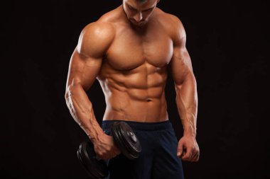 Yakışıklı güç atletik erkek dumbbell ile güvenle iple çekiyor. Altı paket, mükemmel abs, omuzlar, pazı, triceps ve göğüs ile güçlü vücut geliştirmeci izole siyah zemin üzerine