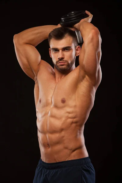 Strong man making exercises on triceps with a dumbbell. Close up shot training hands. Fitness Model showing his Torso with six pack abs. isolated on black background with copyspace — Stock Photo, Image