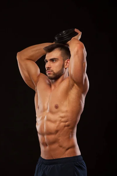 Sterke man maken van oefeningen op triceps met een halter. Close-up shot opleiding handen. Fitness Model toont zijn Torso met zes pack abs. geïsoleerd op zwarte achtergrond met copyspace — Stockfoto