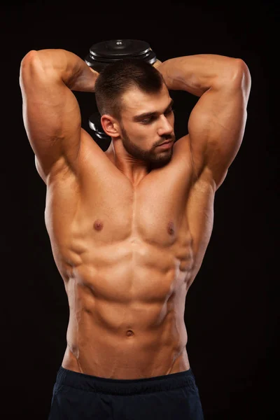 Sterke man maken van oefeningen op triceps met een halter. Close-up shot opleiding handen. Fitness Model toont zijn Torso met zes pack abs. geïsoleerd op zwarte achtergrond met copyspace — Stockfoto